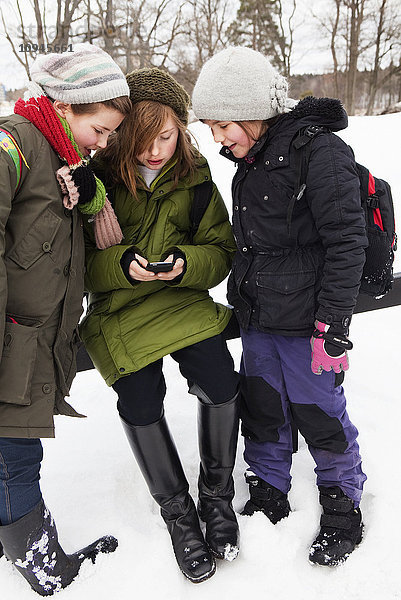 Mädchen mit Mobiltelefon im Schnee