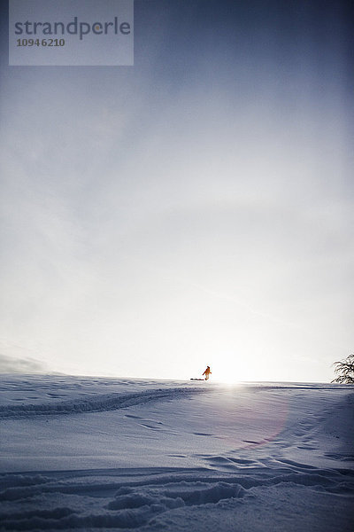 Silhouette einer Person mit Schlitten in einer Winterlandschaft