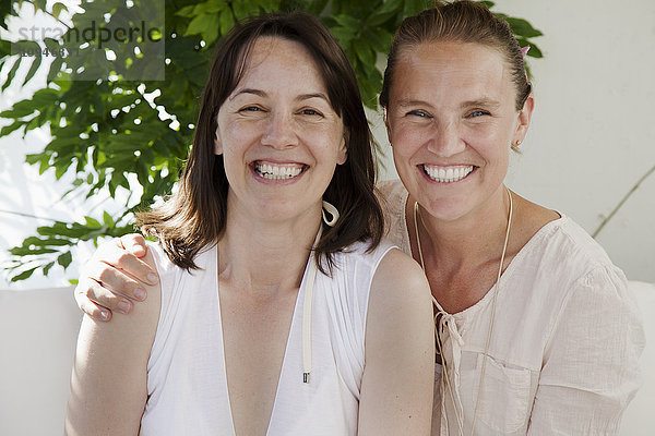 Zwei mittlere erwachsene Frauen posieren zusammen und lächeln