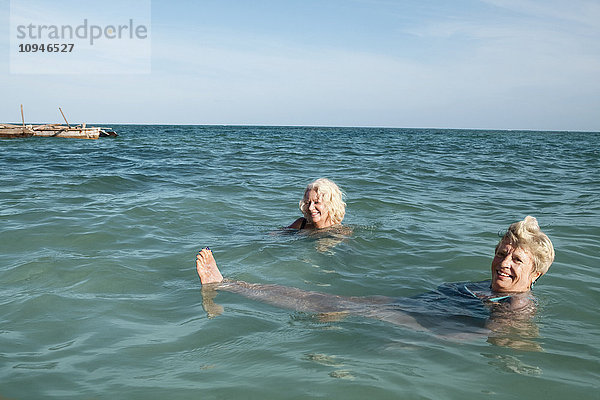Zwei lächelnde Frauen schwimmen im Meer