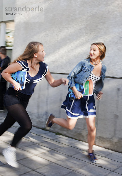Zwei Teenager-Mädchen rennen vor der Schule