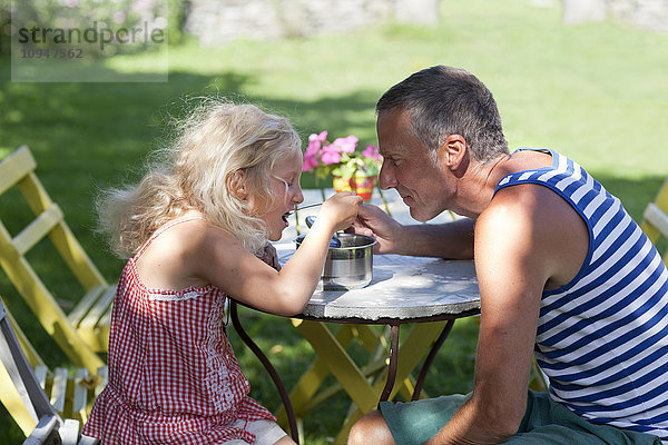 Vater und Tochter essen gemeinsam aus einem Kochtopf