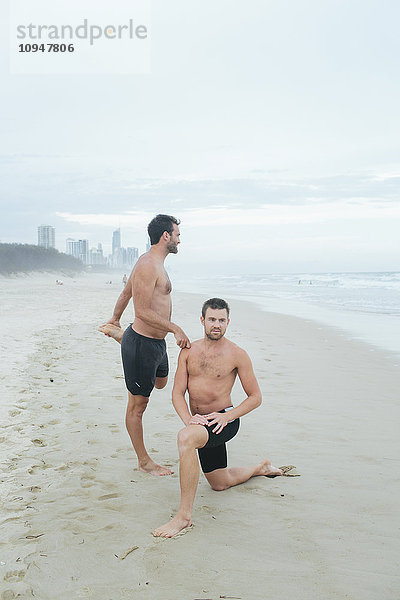 Männer dehnen sich am Strand