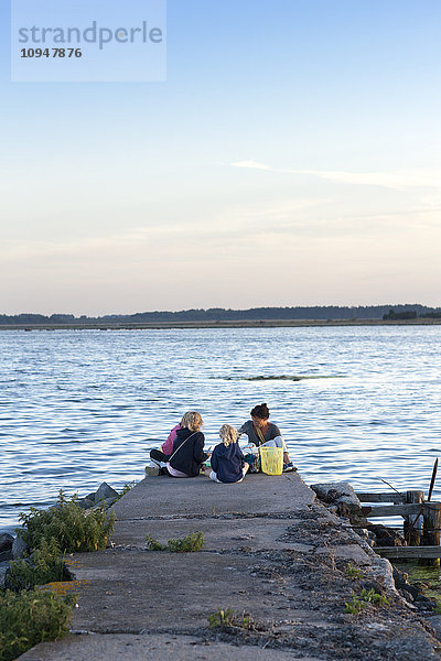 Mutter mit drei Töchtern beim Picknick am Meer