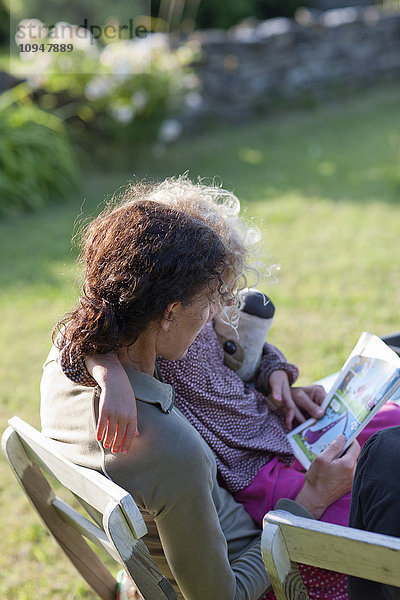 Mutter und Tochter lesen ein Buch auf einem Liegestuhl