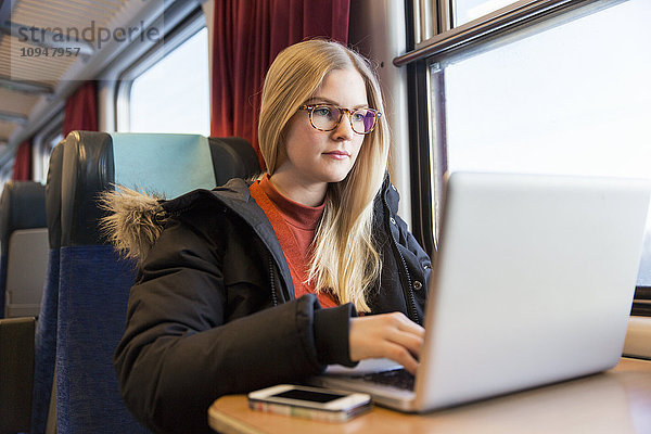 Junge Frau mit Laptop im Zug