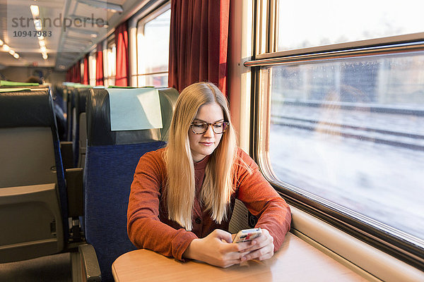 Junge Frau benutzt Mobiltelefon im Zug