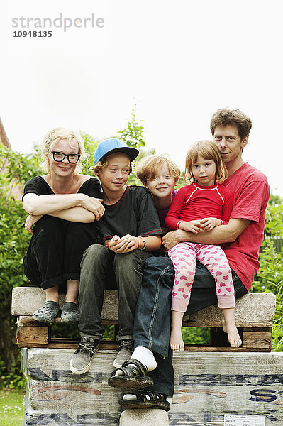 Familie mit drei Kindern sitzt im Park