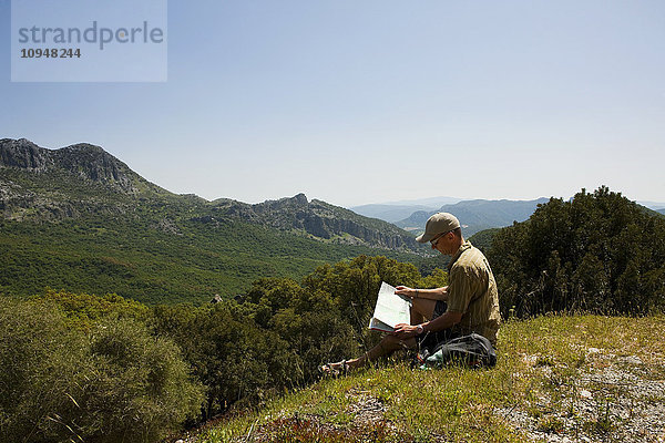 Mann mit Karte auf einem Hügel sitzend