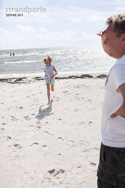 Mädchen läuft am Strand zu ihrem Vater