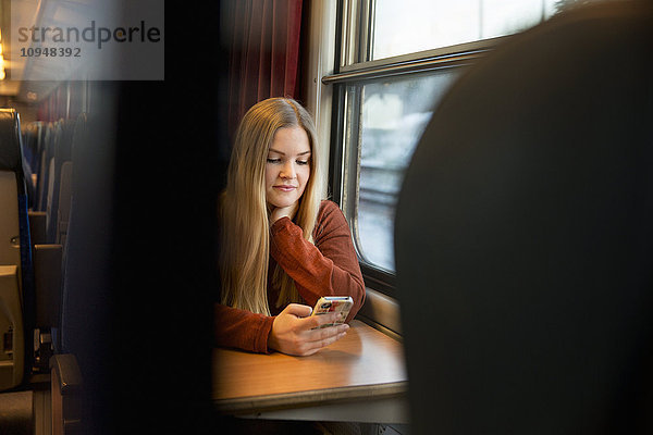 Junge Frau benutzt Mobiltelefon im Zug
