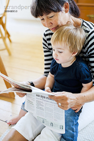 Großmutter mit Enkel beim Zeitungslesen