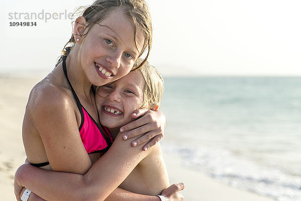 Mädchen umarmen sich am Strand