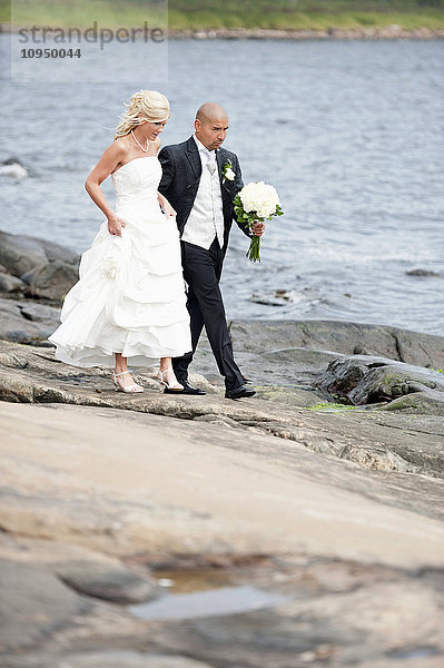 Brautpaar beim Spaziergang an der felsigen Küste