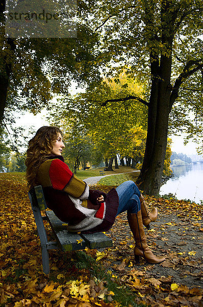 Eine Frau sitzt auf einer Parkbank.