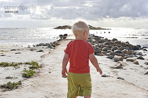 Niedlicher Junge geht am Strand spazieren