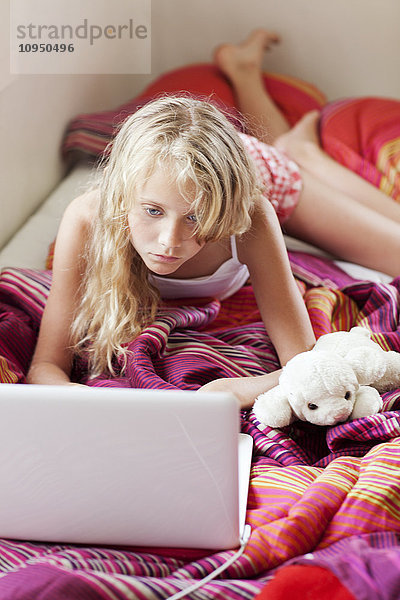 Mädchen mit Laptop auf dem Bett