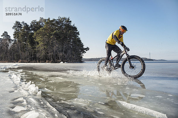 Mann radelt auf einem zugefrorenen See