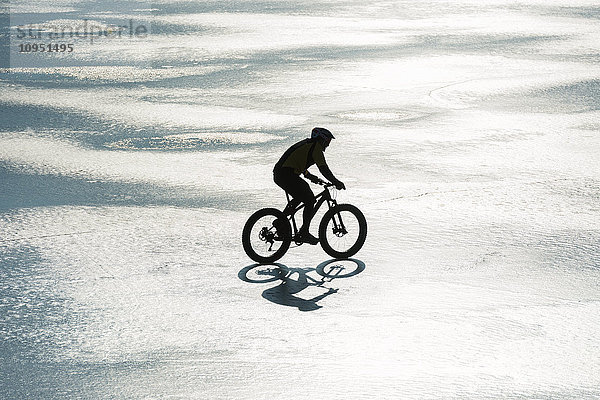 Mann radelt auf einem zugefrorenen See