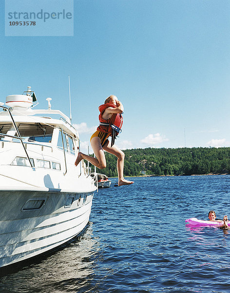 Frau springt von einem Boot ins Wasser.