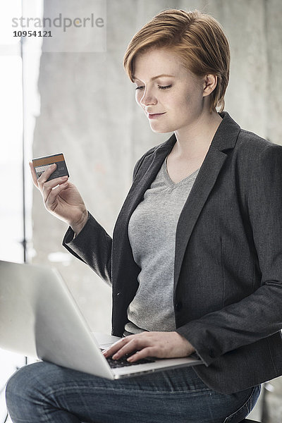 Frau mit Bankkarte am Laptop