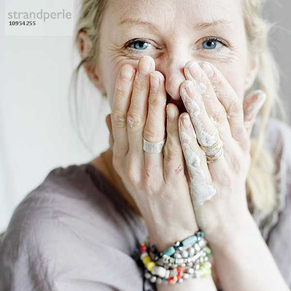 Porträt einer Frau  die den Mund mit den Händen bedeckt