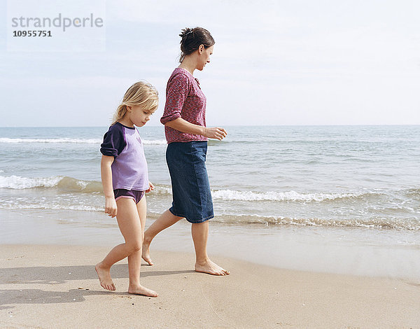 Mutter und Tochter gehen am Strand spazieren