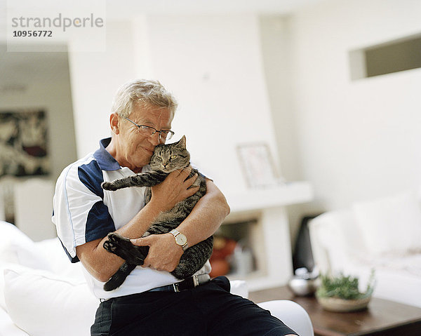 Ein Mann hält eine Katze im Arm  Schweden.