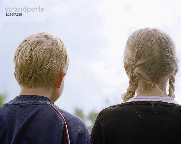 Blondes Mädchen und Junge stehen nebeneinander  Rückansicht  Schweden.