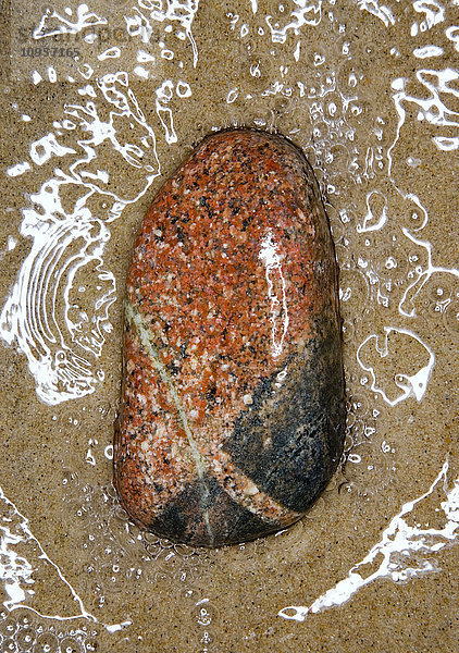 Ein Stein auf Sand am Wasser  Schweden.