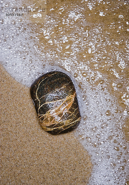 Ein Stein auf Sand am Wasser  Schweden.