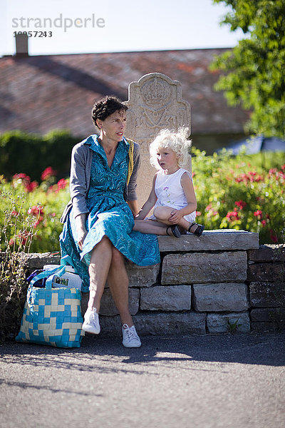 Mutter und Tochter sitzen auf einer Steinmauer  Schweden.