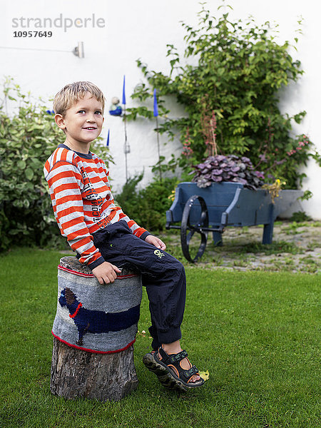 Junge sitzt auf einem Baumstumpf  Schweden.