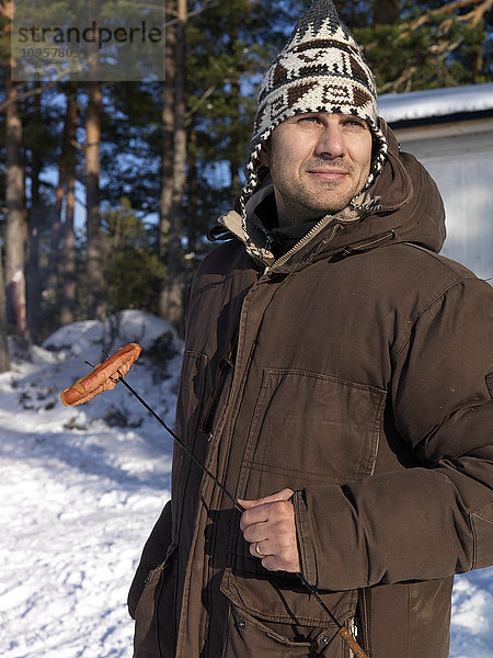 Mann beim Grillen von Hot Dogs im Freien  Schweden.