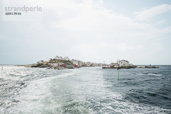 Eine Insel mit dem Kielwasser eines Bootes im Vordergrund  Schweden.