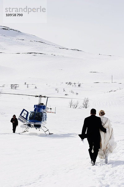 Brautpaar auf dem Weg zu einem wartenden Hubschrauber  Schweden.