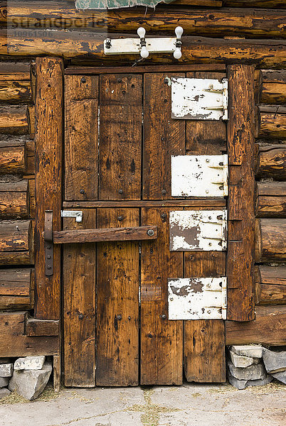 Rustikale  alte Holztür mit großen weißen Metallscharnieren  Tetsa River Lodge  British Columbia  Kanada  Sommer