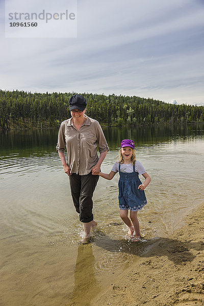 Mutter und Tochter waten mit bloßen Füßen im Lucky Lake  Yukon Territory  Kanada  Sommer