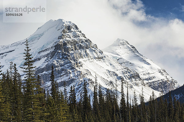 Nahaufnahme von zwei schneebedeckten Berggipfeln mit Wolkendecke und etwas blauem Himmel; Banff  Alberta  Kanada'.