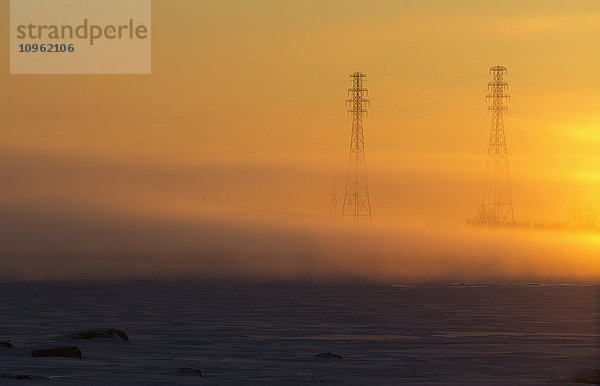 Strommasten im Nebel bei Sonnenaufgang am Ufer des St.-Lorenz-Stroms; Les Cedres  Quebec  Kanada