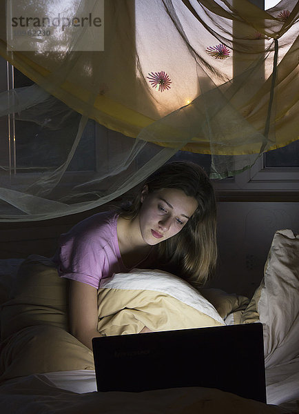 Teenager-Mädchen an ihrem Computer im Bett; England'.