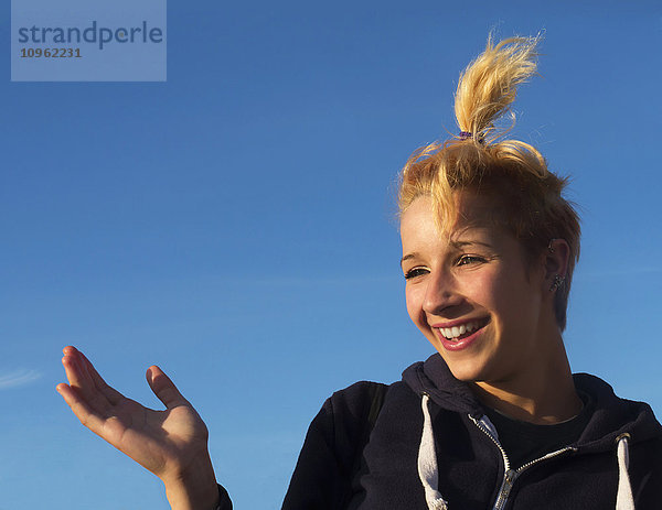 Teenager-Mädchen lachend vor blauem Himmel; England'.