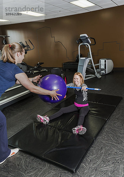 Physiotherapeutin  die einer jungen Frau mit einer Rückenmarksverletzung bei der Durchführung von Übungen zum Werfen eines Widerstandsballs hilft; Edmonton  Alberta  Kanada .