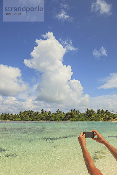 Frau fotografiert ein Atoll mit einem Smartphone; Insel Medahutthaa  Nord-Huvadhoo-Atoll  südliche Malediven'.