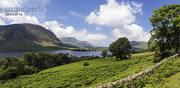 Ein ruhiger See mit Bergen und einer Steinmauer im Vordergrund; Cumbria  England'.