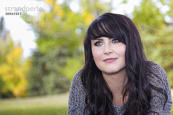 Porträt einer schönen jungen Frau im Freien in einem Stadtpark im Herbst; St. Albert  Alberta  Kanada'.