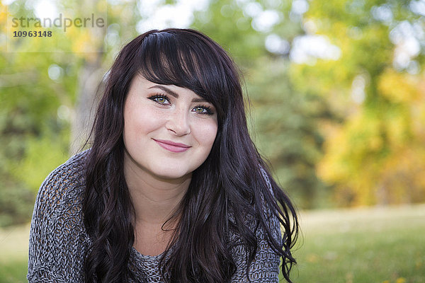 Porträt einer schönen jungen Frau im Freien in einem Stadtpark im Herbst; St. Albert  Alberta  Kanada'.