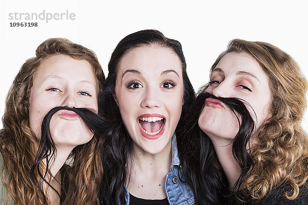 Drei junge Frauen in humorvoller Pose mit langen Haaren als Schnurrbart; Alberta  Kanada