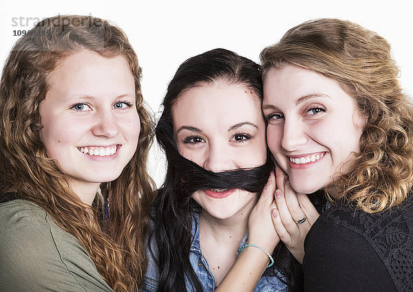 Drei junge Frauen in humorvoller Pose mit langen Haaren als Schnurrbart; Alberta  Kanada