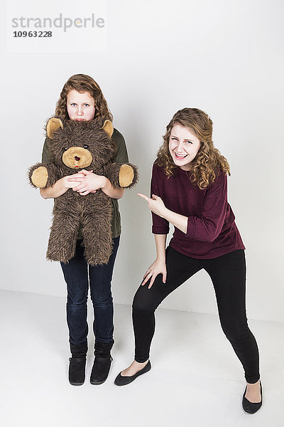 Studioaufnahme einer Freundin  die sich über eine andere Freundin lustig macht  die ihren Teddybär hält; Alberta  Kanada'.
